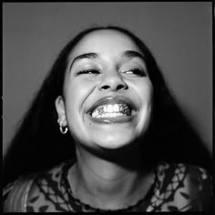 a black and white photo of a woman with braces on her teeth smiling at the camera