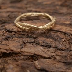 a gold ring sitting on top of a piece of wood with no one around it