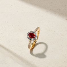 A glowing red ruby lays at the center of this meticulously crafted ring that's framed by a halo of twinkling round and baguette diamonds. Additional petite round diamonds sparkle along each end of the comfort fit shank to complete the look. Make this elegant and timeless adornment apart of your everyday jewelry rotation. Metal: 18kt Gold Ruby Weight: 0.60 ct. Round Diamond Weight: 0.25 ct. Baguette Diamond Weight: 0.22 ct. Measurements: 10.0 mm length *Please note that the listed ct. weights are Red Baguette Cut Diamond Ring, Red Diamond Ring With Baguette Cut, Red Baguette Cut Lab-created Ruby Ring, Red Diamond Baguette Cut Rings, Red Baguette Cut Ruby Ring, Classic Red Diamond Ring, Baguette Cut, Baguette Cut Ruby Ring With Diamond Center Stone, Baguette Cut Ruby Ring With Diamond, Classic Red Baguette-cut Diamond Ring