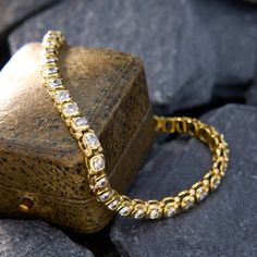 a gold chain bracelet sitting on top of a rock