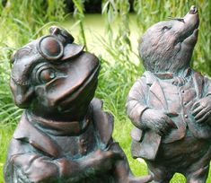 two statues of mice sitting on top of each other in front of some grass and plants