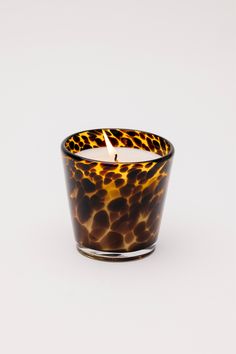 a candle that is sitting on top of a white surface with an animal print pattern