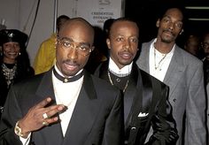 three men standing next to each other wearing suits and bow ties with one pointing at the camera