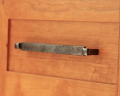 a close up of a drawer handle on a wooden cabinet