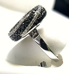 Dainty and darling, this black and white diamond fashion ring is a great anytime look. Created in warm 14K White gold, this ring features a center cluster of alluring enhanced black diamonds with a frame of shimmering white accent diamonds. Simple yet so stylish, this ring delights with a very amazing gallery of flowery shape and a polished shine. Details: ►Metal: White Gold ►Gold Purity: 14K ►Diamond Weight: 2.50 carat ►Diamond Shape: Round Brilliant ►Diamond Clarity & Grade: GH-SI1 ►White Black Diamond Ring With Halo Setting For Anniversary, Black Oval Rings With Brilliant Cut, Elegant Rings With Black Diamonds, Black Sapphire Ring With Brilliant Cut For Fine Jewelry, Black Diamond Ring With Halo Setting For Formal Events, Black Diamond Ring With Halo Setting For Formal Occasions, Black Sapphire Ring With Diamond Accents For Wedding, Formal Black Diamond Ring With Halo Setting, Black Diamond Rings For Evening