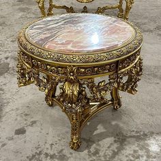 an ornately decorated table and chair in the middle of concrete floored area with no one sitting on it