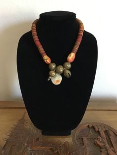 This is a unique piece as I have used Vinyl from Africa.  Cut into circles it makes an interesting piece.  Also two large Coral beads, Brass Beads and a hanging piece of Abalone with orange markings.  Measures 19" with Brass Clasp. Unique Dangling Beads, Unique Large Beads For Festival, Unique Brown Beaded Necklace With Polished Beads, Unique Beaded Necklaces With Wooden Beads, Unique Necklace With Oval Wooden Beads, Unique Brown Polished Beads, Unique Orange Jewelry With Wooden Beads, Unique Jewelry With Dangling Round Beads, Unique Beaded Necklace With Round Wooden Beads