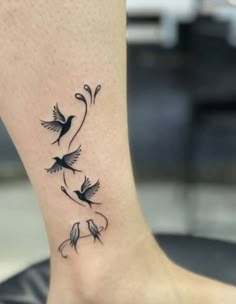 a small tattoo on the foot of a woman with two birds flying over it and vines