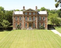 an aerial view of a large red brick house in the middle of a green field