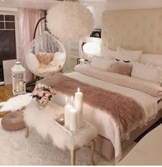 a bedroom with a large bed and white fur on the headboard, two candles in front of the bed