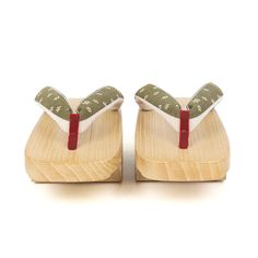 pair of wooden shoes with green and white fabric on the soles, side view