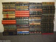 a large stack of books sitting on top of a table next to a wall mounted clock