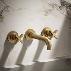 two gold faucets on a marble counter top