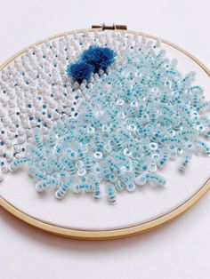 a close up of a embroidery on a white surface with blue and white beading