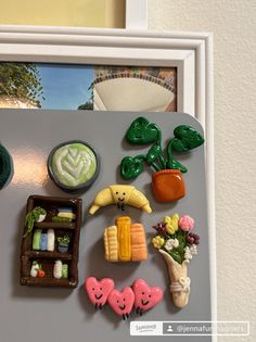 there is a magnet board with food on it and pictures in the frame behind it