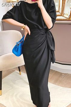 a woman wearing a black dress and holding a blue purse in front of her face