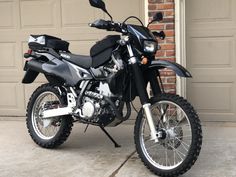 a dirt bike parked in front of a garage door next to a brick building with two doors