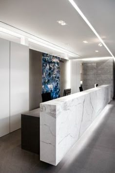 a white marble reception counter in a modern office building with lights on the ceiling and walls