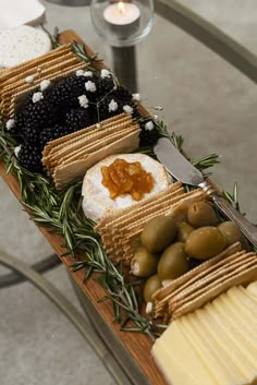 an assortment of cheeses, crackers and olives on a wooden platter