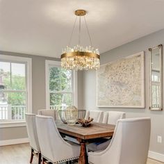 a dining room table with white chairs and a chandelier