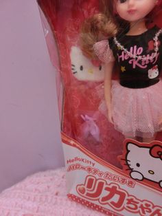 the hello kitty doll is in its pink box and has a black shirt on it