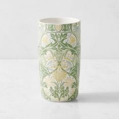 a green and white vase sitting on top of a marble countertop next to a wall