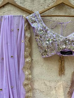 A three-piece lavender lucknowi mirror lehenga set from the Priti Sahni collection. This elegant lavender georgette lehenga with heavy gota, sequins, pearl and zari work border is paired with lavender blouse in raw silk fabric with mirror, pearl and zardozi hand work embroidery. The lehenga has side hanging ball tassels to the waistline. And the blouse has a sequins tassel tie-up at the back. The outfit is completed with a lavender mirror net dupatta with scalloped edging. Unstitched Lavender Sets With Dupatta, Lavender Sets With Dupatta For Eid, Lavender Eid Sets With Dupatta, Lavender Eid Set With Dupatta, Lavender Eid Outfit Set With Dupatta, Unstitched Bollywood Lavender Sets, Unstitched Lavender Bollywood Sets, Lavender Bollywood Style Sets, Fitted Lavender Blouse Piece For Festive Occasion