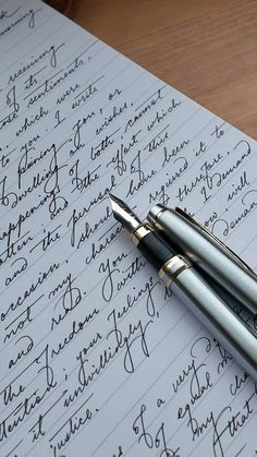 two fountain pens sitting on top of a piece of paper that has writing on it