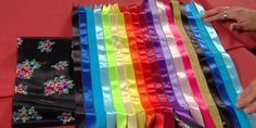 many different colored ribbons are lined up on a red tablecloth with one folded and the other unwrapped