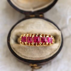 Piece Details Metal: 18k yellow gold Size: 7 3/4, may be resized Gram Weight: 4.1 grams Hallmarks: English hallmarks, Birmingham assay marks Period: Antique (circa 1918) Stone Details Stone: Ruby Cut/Shape: 5 square  Total Carat Weight: 0.80 carat Why We Love It This antique five stone ring is a quintessential example of the Victorians' favorite ring style. Crafted in 1918, nearly 20 years after the end of Queen Victoria's reign, the ring represents a return to the refined elegance of the Victorian era, which had fallen out of fashion with the rise of artistic movements at the end of the 19th century. Forged in 18 karat yellow gold, with assay marks for 1918, it features five square cut rubies that seem to glow from the inside out. Vintage Yellow Gold Ruby Ring With Diamond Cut, Classic Gold Ruby Ring With Diamond Cut, Antique 14k Stamped Yellow Gold Ruby Ring, Victorian 14k Yellow Gold Ruby Ring, Victorian Style 14k Yellow Gold Ruby Ring, Victorian Ruby Ring In 14k Yellow Gold, Ceremonial Yellow Gold Ruby Ring, Elegant Anniversary Rings With Maker's Mark, Antique 14k Yellow Gold Ruby Ring