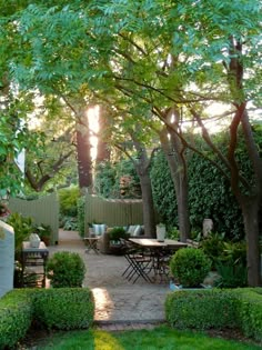 an outdoor garden with trees, bushes and tables