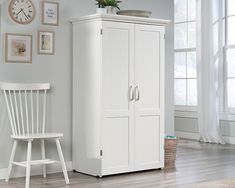 a white armoire next to a chair in a room