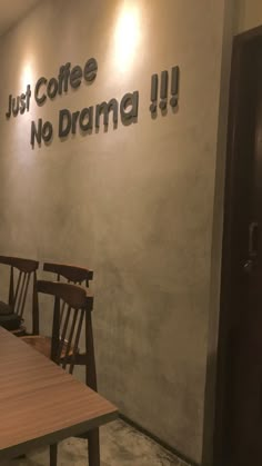 a wooden table and chairs in front of a sign that says just coffee no drama