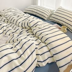 an unmade bed with blue and white striped sheets