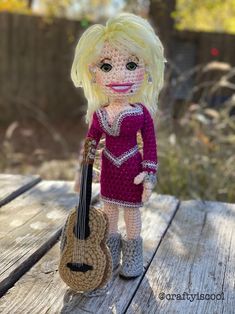 a crocheted doll is holding a guitar