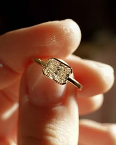 a person holding a ring with a diamond in it's middle finger and fingers