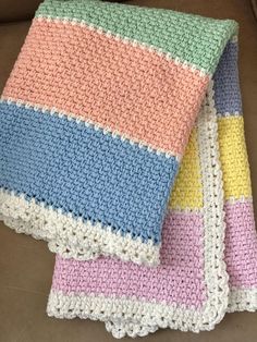 two crocheted blankets sitting on top of a couch