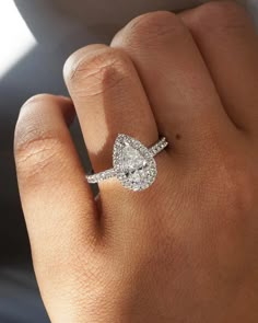 a woman's hand with a diamond engagement ring on her left hand, and an oval shaped diamond in the middle