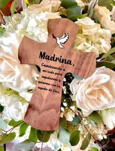 a wooden cross surrounded by white flowers and greenery with the words madonna written on it