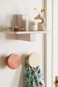 two shelves with candles and other items on them in the corner of a white room