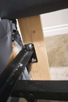 the back end of a black chair with wood and metal frame on carpeted floor