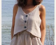 a woman standing next to the ocean wearing a dress