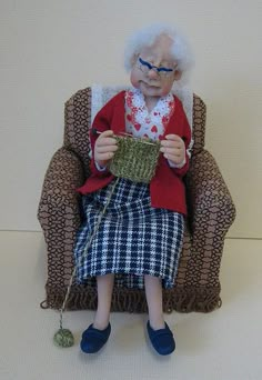 an old woman sitting in a chair holding a cup