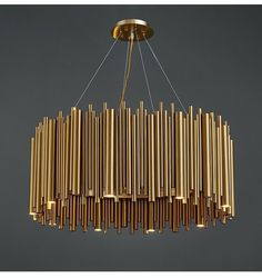 a large chandelier made out of brass tubes hanging from a ceiling light fixture