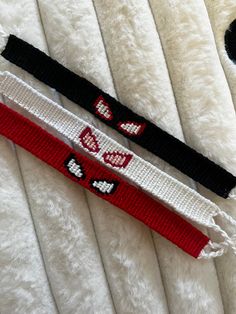 two white and black bracelets laying on top of a bed next to each other