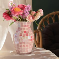 a vase filled with flowers sitting on top of a table next to a wooden chair