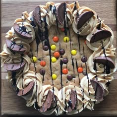 a cake decorated with chocolate, candy and marshmallows on a wooden table