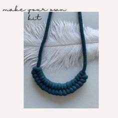 a blue necklace with white feathers hanging from it's sides and the words make your own kit