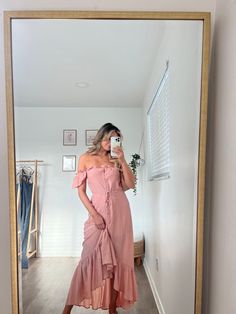 a woman taking a selfie in front of a mirror wearing a pink off the shoulder dress