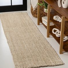 a large rug is on the floor next to a table and bookshelf in a room